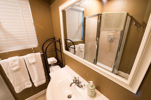 A bathroom with a white sink, a mirror, and a towel rack with white towels.