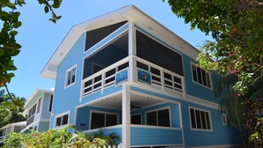 Un edificio de dos pisos con fachada azul y detalles blancos. Cuenta con varias ventanas y balcones.