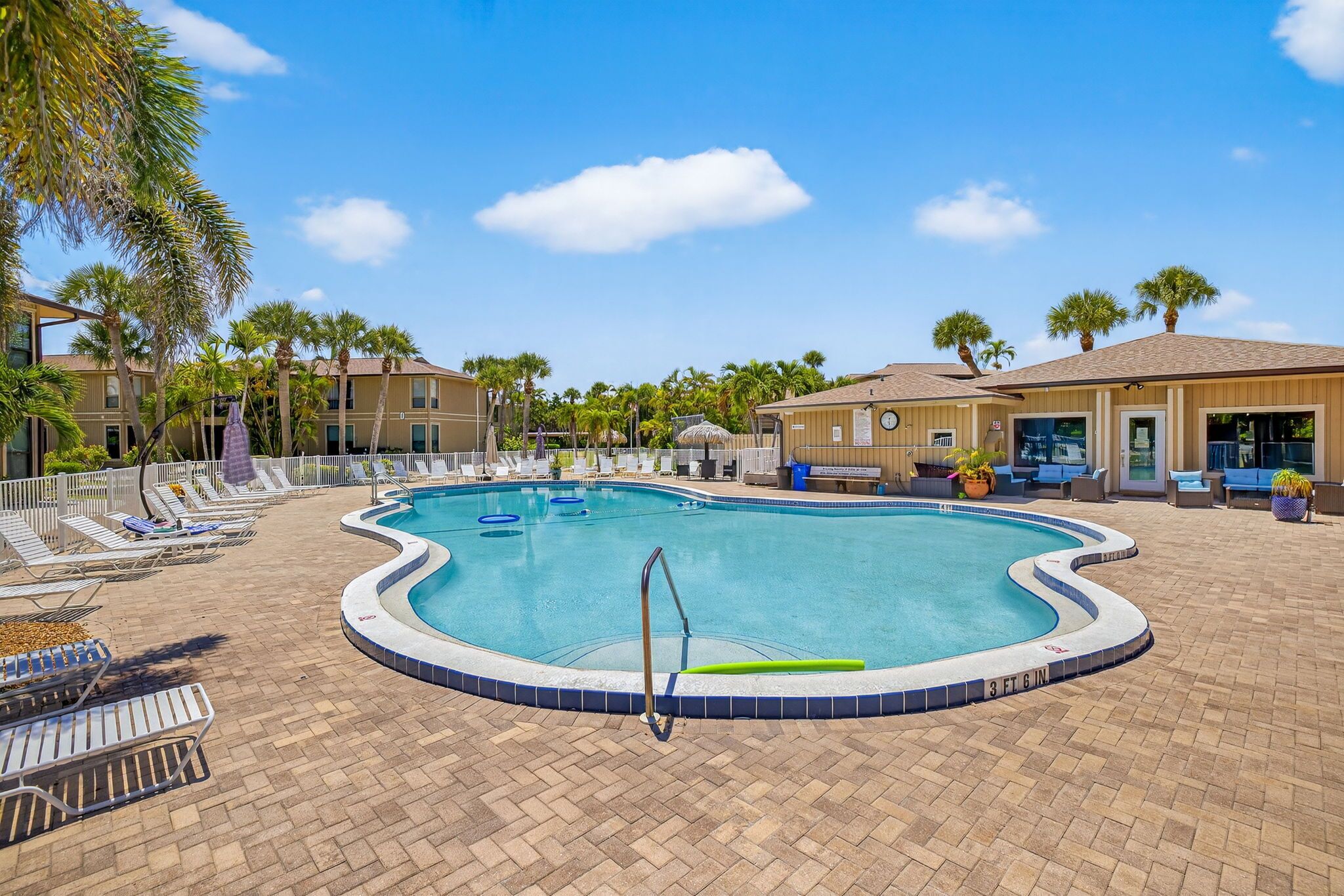 A swimming pool with lounge chairs and palm trees.