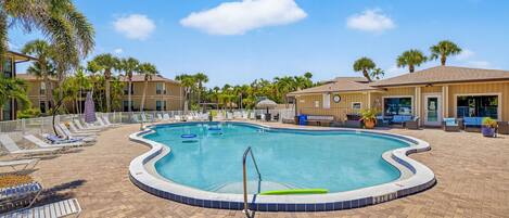 A swimming pool with lounge chairs and palm trees.