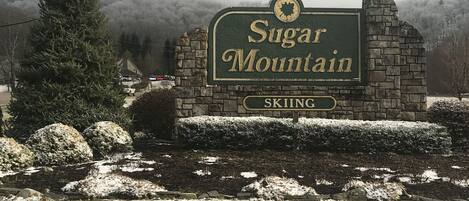 Schild für Sugar Mountain, mit einer Steinmauer und schneebedecktem Boden.
