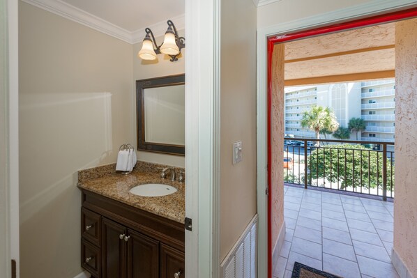 A bathroom with a granite countertop sink, a mirror, and a towel rack. - Tropical Oasis and private beach on the exclusive Holiday Isle in Destin, FL (Destin)