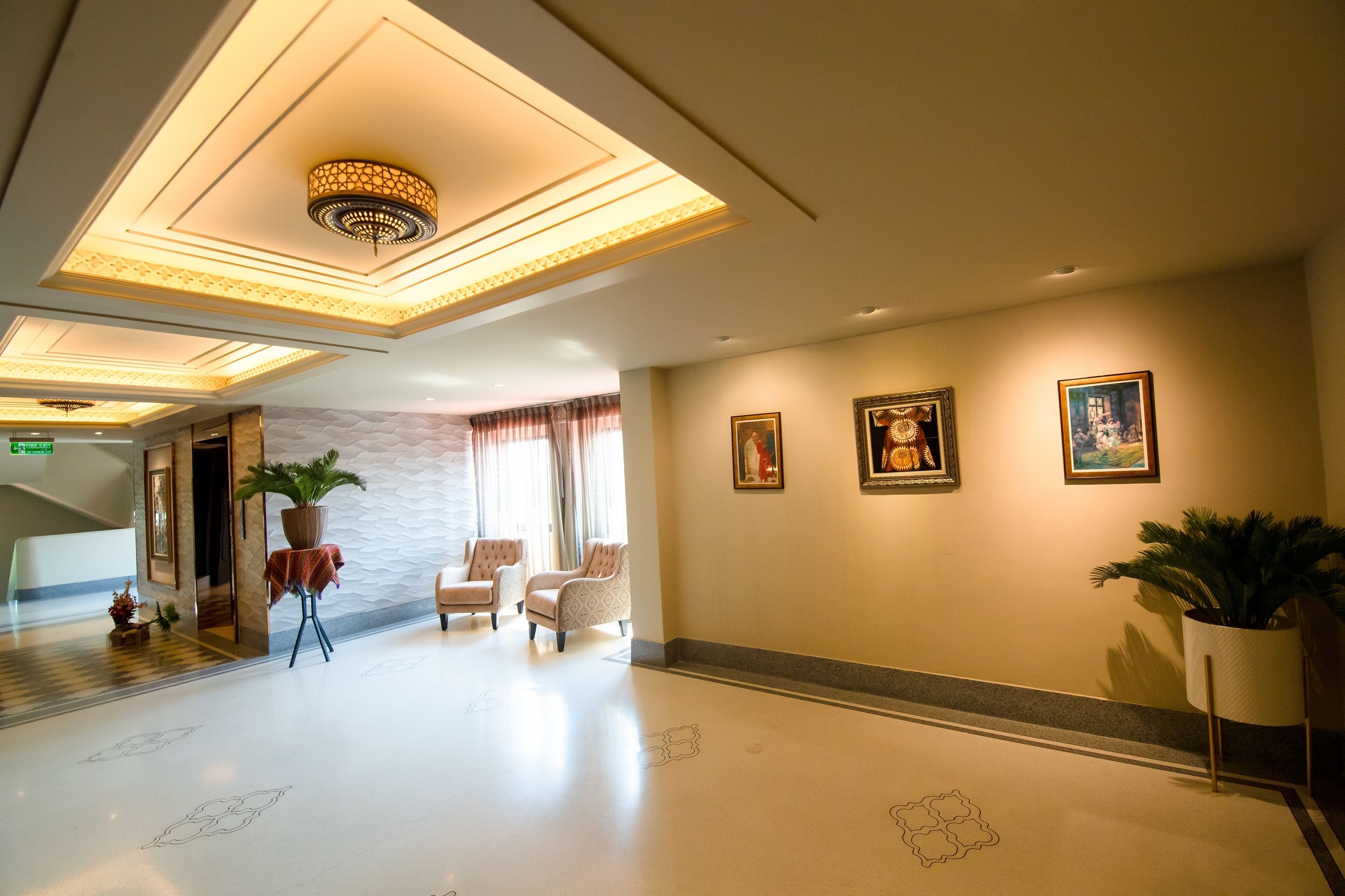 Eine Hotelhalle im modernen Design mit einer Rezeption, einer Sitzecke mit Sesseln und dekorativer Beleuchtung.