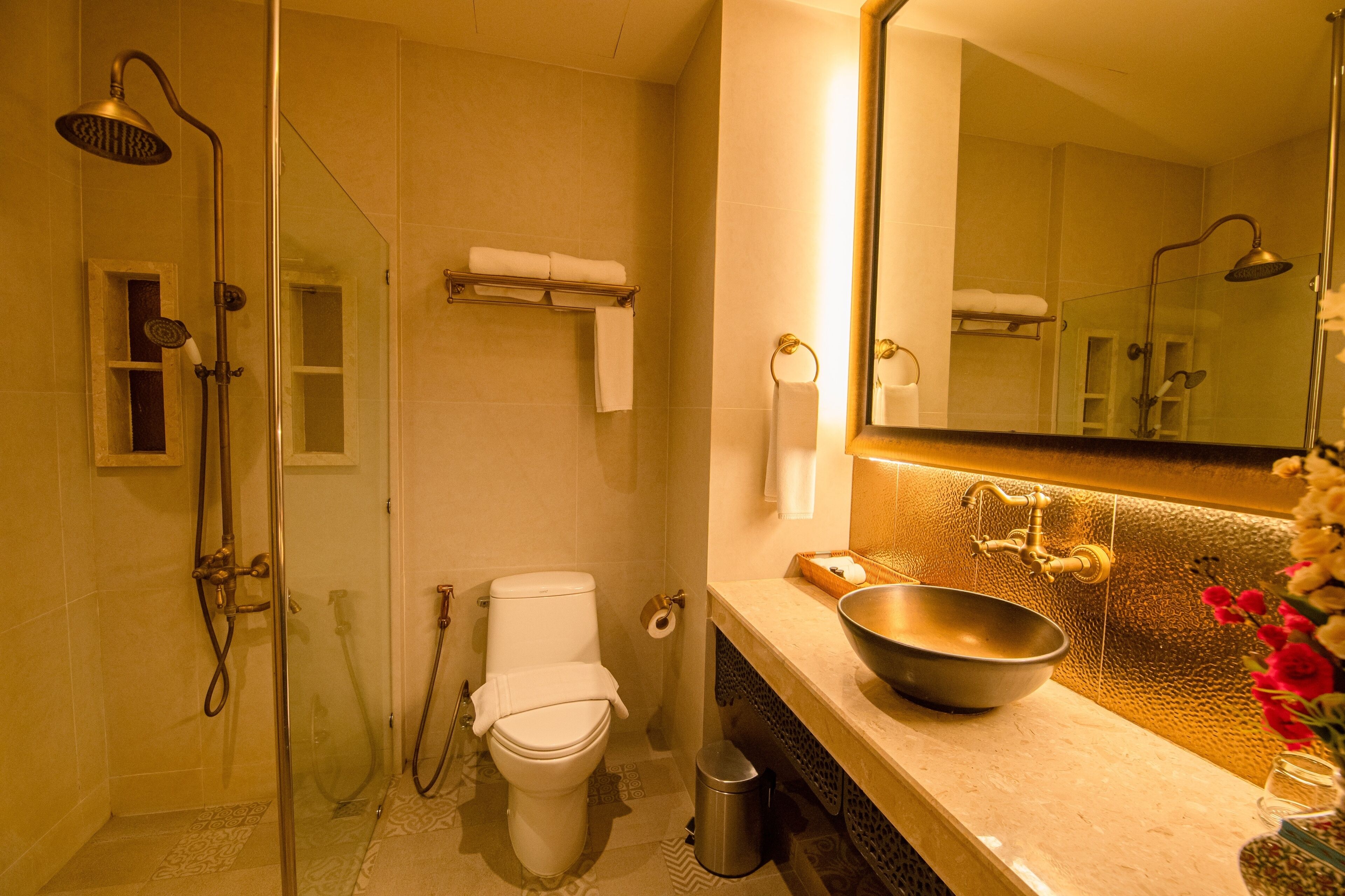 Une salle de bain avec une douche à parois de verre, des toilettes, un lavabo et un miroir.