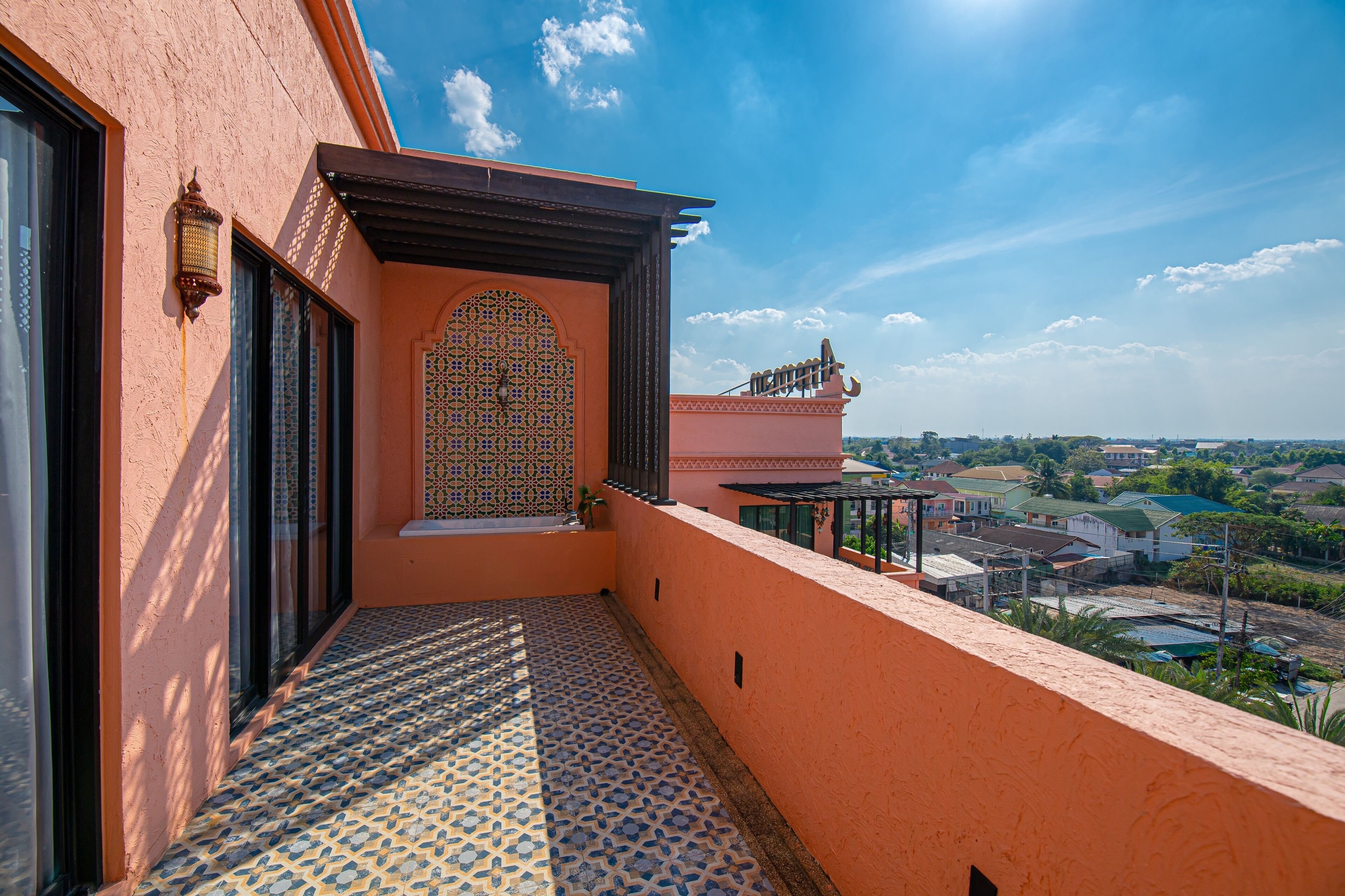 A balcony with a patterned floor, a decorative door, and a view of a residential area.