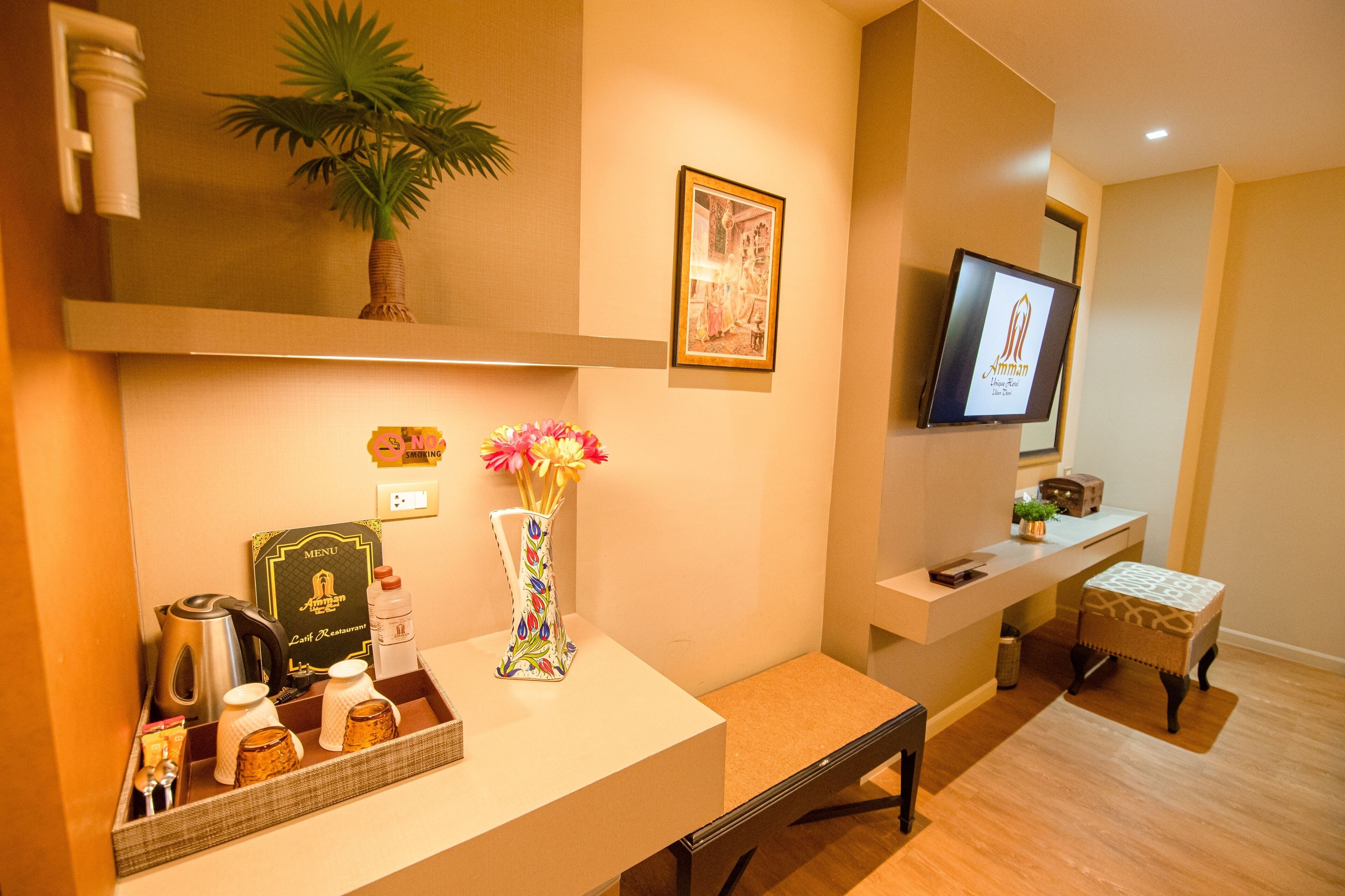 Habitación de hotel con minibar, televisión, un cuadro enmarcado y una pequeña mesa con una planta.