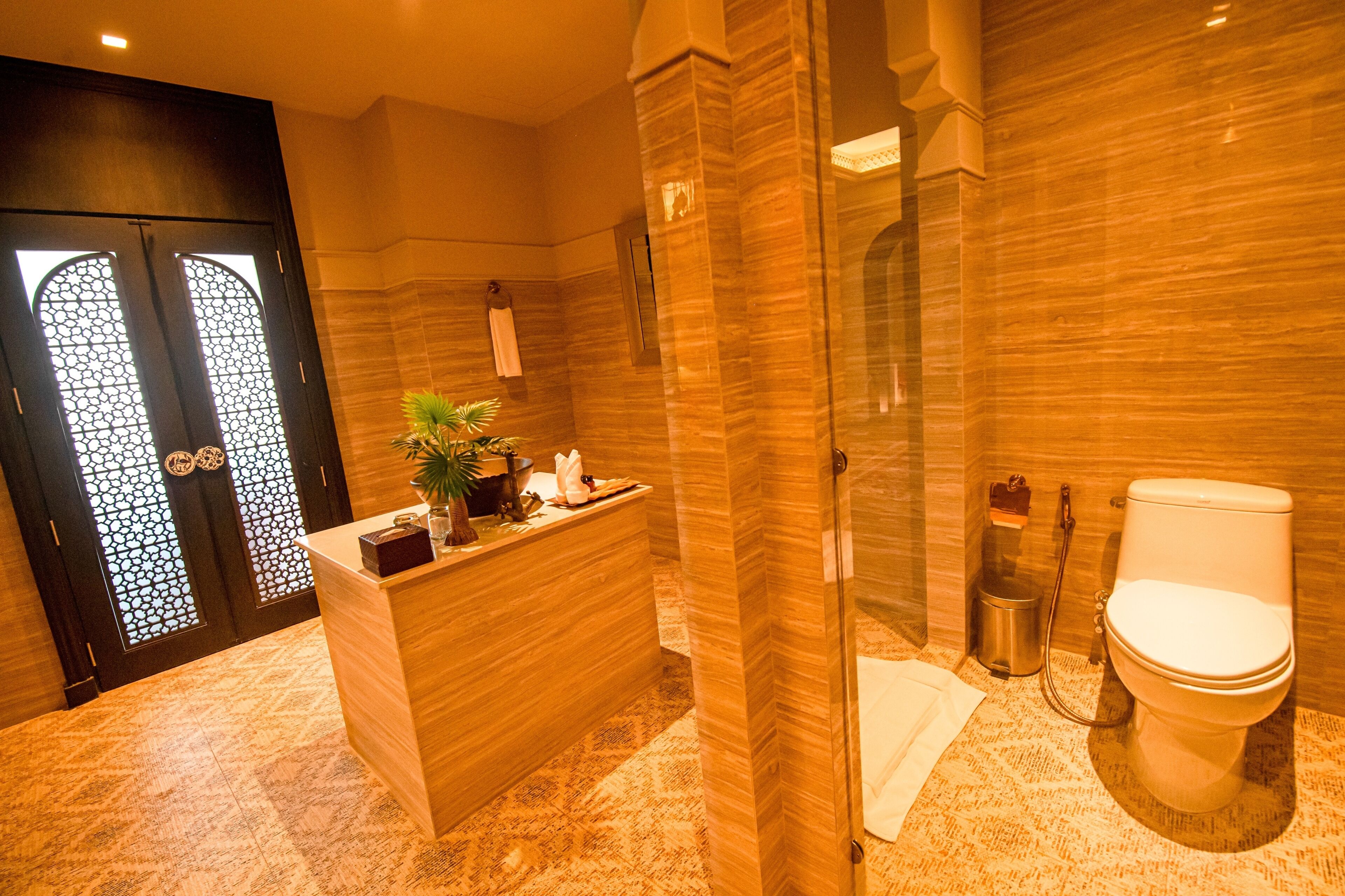 A modern bathroom with a marble floor, a reception desk, a toilet, and a glass shower enclosure.