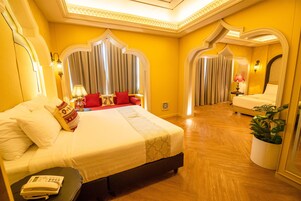 A hotel room with a large bed, a bedside telephone, and a potted plant.