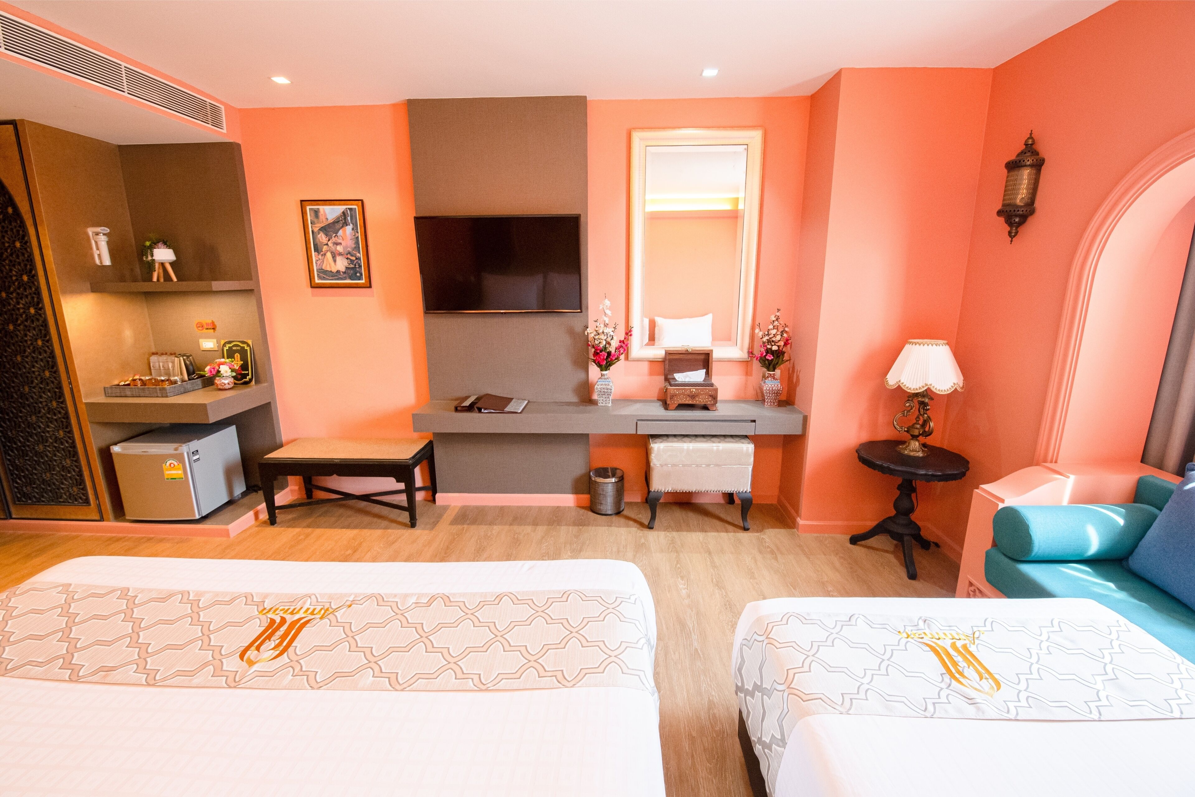 Une chambre d’hôtel avec deux lits, un bureau avec un ordinateur, une télévision et une petite table avec une lampe.