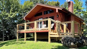 A wooden cabin with a deck, surrounded by trees. - 390 Reviews ❤️ Mtn Top Getaway! Views, 2 Decks, Hot tub, Recliners, Privacy (Pigeon Forge)