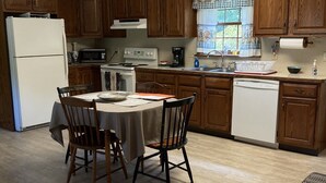 A kitchen with wooden cabinets, a refrigerator, stove, microwave, and a dining table with chairs. - Apartment in scenic Hudson Valley New York (Verbank)