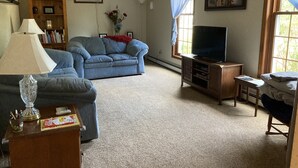 A living room with a blue sofa, a television, a lamp, a bookshelf, and a window with curtains. - Apartment in scenic Hudson Valley New York (Verbank)