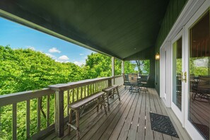 Eine Holzterrasse mit Bänken, einem Tisch und Stühlen mit Blick auf eine üppige grüne Landschaft.