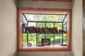 Ein Bücherregal mit Büchern und einem gerahmten Bild in einem Fenster mit Holzrahmen.