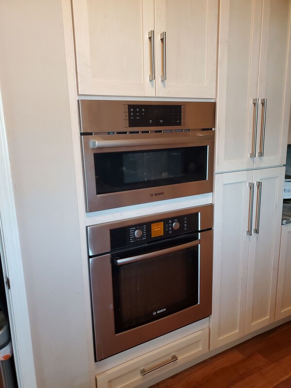 A kitchen with a Bosch oven, a microwave, and a refrigerator.