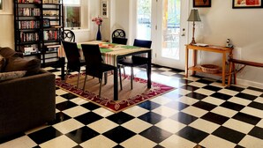 Un coin repas avec un sol à carreaux, une table à manger avec des chaises, une bibliothèque et un ventilateur de plafond.