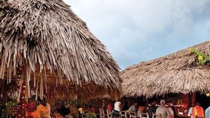 Ein Restaurant am Strand mit Reetdächern und Holztischen.