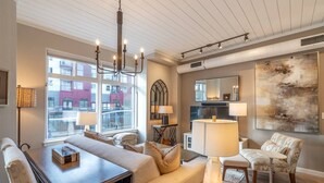 A modern living room with a sofa set, a dining table, and a chandelier.