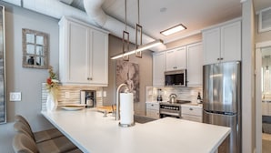 A modern kitchen with white cabinets, stainless steel appliances, and a central island with seating.
