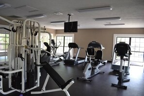A gym with various exercise machines, a television mounted on the ceiling, and large windows allowing natural light. - Upgraded condo in the heart of McCormick Ranch (Scottsdale)