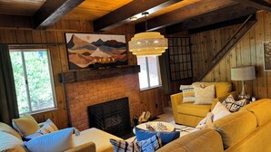A cozy living room with a fireplace, wooden walls, and a chandelier. - Perfect Sierra Cabin Retreat - Near Rivers, Lakes, and Mountains (Twin Bridges)