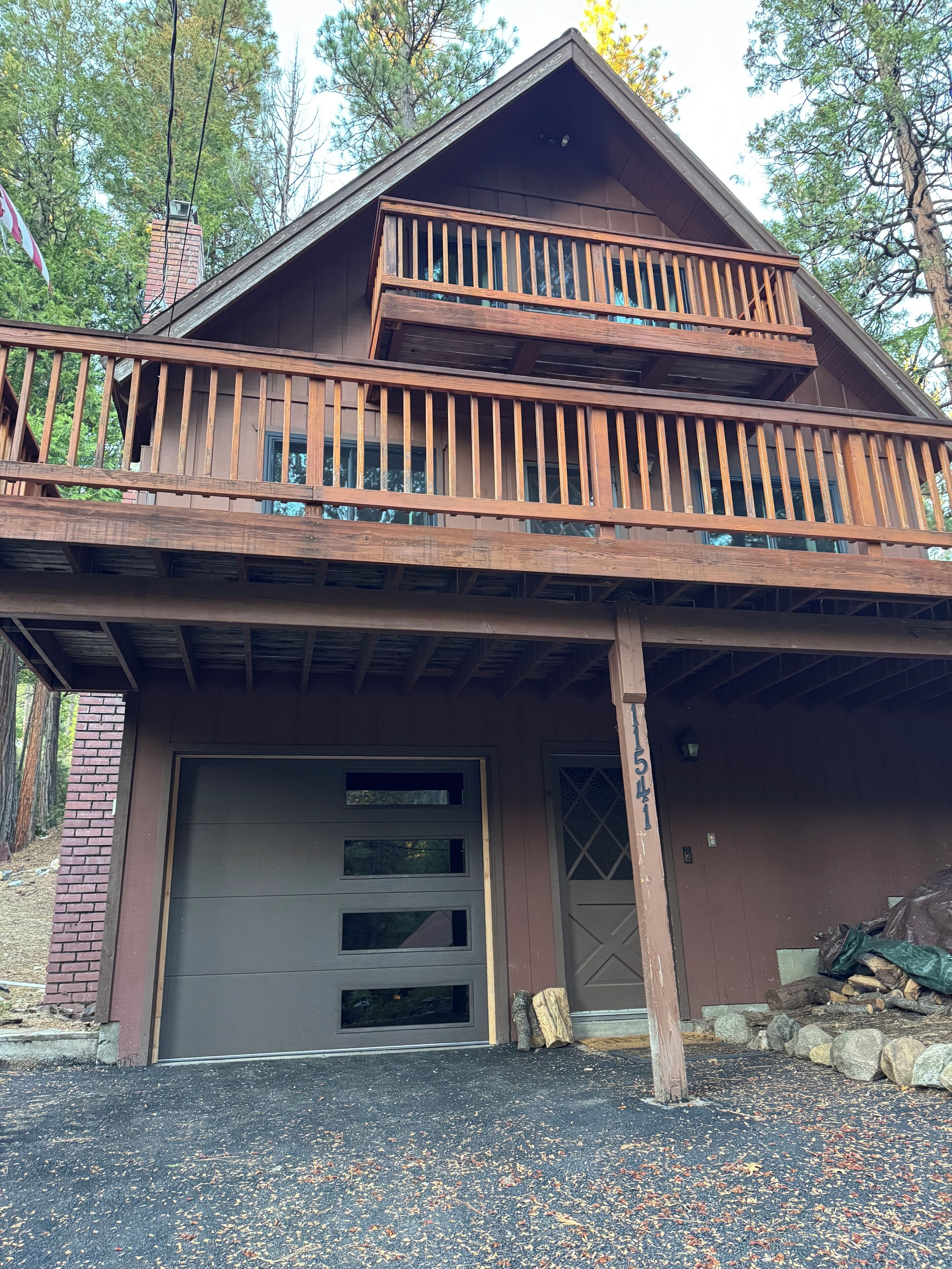 A two-story cabin with a balcony, a garage, and a chimney.