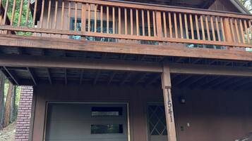 A two-story cabin with a balcony, a garage, and a chimney.
