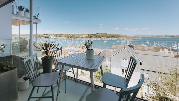 Un balcon avec une table et des chaises donnant sur une marina où sont amarrés des bateaux.