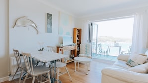 Un salon moderne comprenant un coin repas, un canapé et une vue sur la mer.