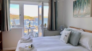 Une chambre d’hôtel avec un lit, un ventilateur et une vue sur les bateaux qui naviguent.