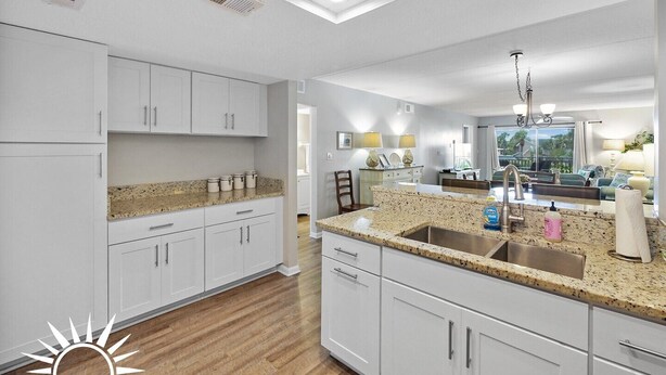 A modern kitchen with white cabinetry, granite countertops, and a stainless steel sink. - Island South 27- Updated, Spacious 2 bedroom condo with ocean view, pool and (St. Augustine)
