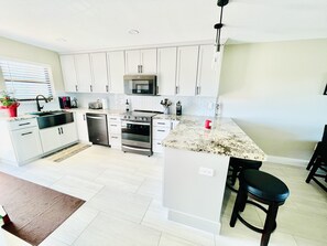 A modern kitchen with white cabinets, a built-in microwave, a stainless steel stove, and a granite countertop.