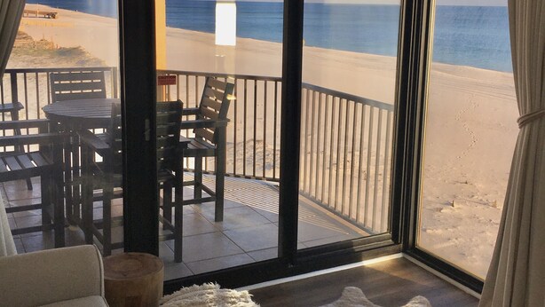 A room with a view of the beach, a table with chairs, and a large window. - Upgrades Galore! STUNNING Views, Steps to the Sand & Short Walk to FLORA-BAMA!! (Orange Beach)