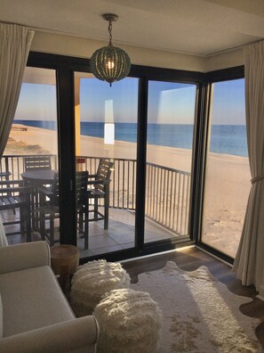 Une pièce avec vue sur la plage, une table avec des chaises et une grande fenêtre.