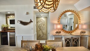 A dining area with a wooden table, a decorative bowl in the center, a fireplace, and a mirror with a wooden frame. - Upgrades Galore! STUNNING Views, Steps to the Sand & Short Walk to FLORA-BAMA!! (Orange Beach)