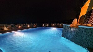 A swimming pool at night with illuminated edges and a water fountain. - Upgrades Galore! STUNNING Views, Steps to the Sand & Short Walk to FLORA-BAMA!! (Orange Beach)