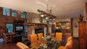 A spacious living room with a stone fireplace, leather furniture, and a television.