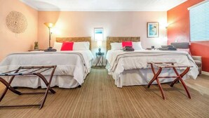 A hotel room with two beds, a small table, a lamp, and a decorative wall piece.