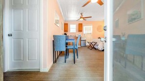A room with a dining area, a kitchenette, and a ceiling fan.