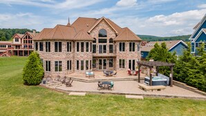 Une grande maison en pierre dotée d’un vaste patio, d’un espace salon extérieur et d’un jacuzzi.