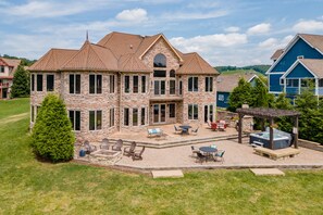 A large stone house with a patio, outdoor seating, and a hot tub.