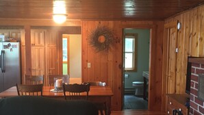Un interior de cabaña acogedor con comedor, sala de estar con sofá y cocina con armarios de madera.