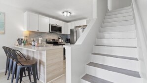 Une cuisine moderne avec des meubles blancs, un îlot central et des appareils électroménagers en acier inoxydable.