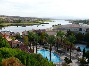 Un resort con piscina, palmeras y vista a un lago.