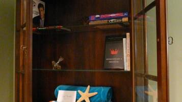 Un mueble de madera con puertas de vidrio, que contiene libros, una estrella de mar y un objeto a rayas.