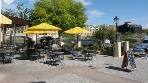 An outdoor café with tables and yellow umbrellas, surrounded by greenery and buildings in the background. - TRANQUIL SETTING IN 6TH FLOOR, 1 BEDROOM 1 BATH CONDO WITH BREATHTAKING VIEW  (Henderson)