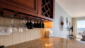 A kitchen with granite countertops, wine glasses hanging above, a wine rack, and a view of the ocean through a large window. - Wow!!!  Updated Beach front 4th top flr condo RIGHT on the beach (Destin)