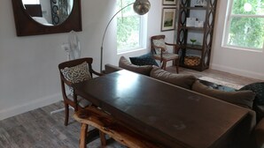 A dining area with a wooden table and benches, a sofa with patterned cushions, and a large mirror on the wall. - Texas Loft is an upstairs studio efficiency apartment (McKinney)