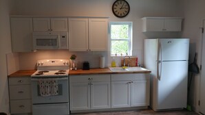 A kitchen with white cabinets, a stove, a microwave, a sink, and a refrigerator. - Texas Loft is an upstairs studio efficiency apartment (McKinney)