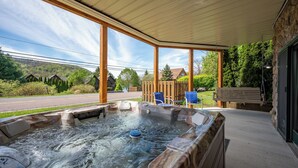 Een bubbelbad onder een overdekte patio met uitzicht op een weg en huizen.